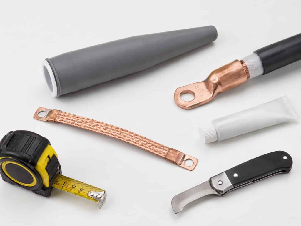 Medium voltage cable termination kit components including cold shrink tubing, stress cone and copper connector laid out for installation