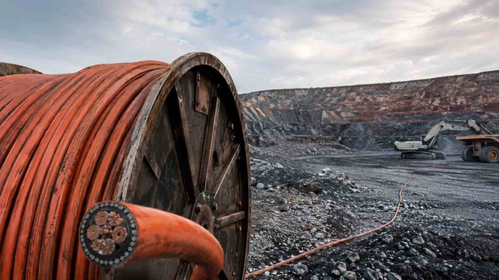 Heavy duty trailing mining cable on a drum at a surface mining operation with excavator machinery in background